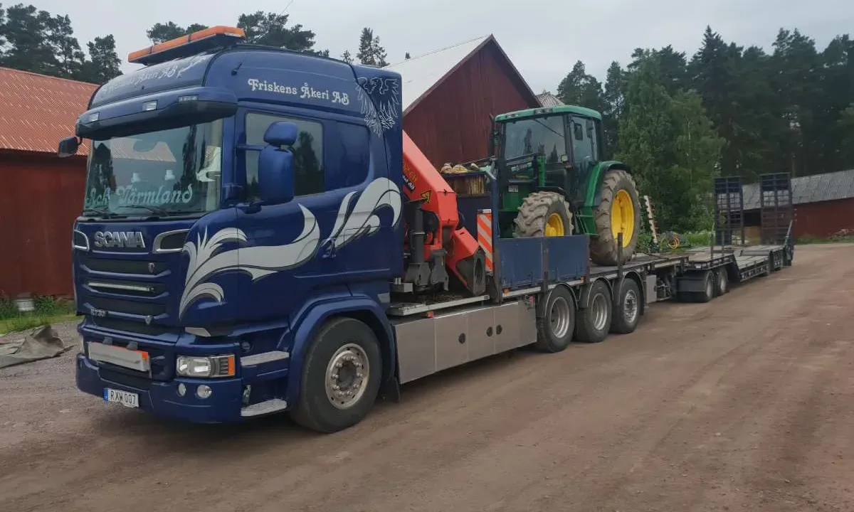 Lastbil med maskintrailer som transporterar en stor maskin